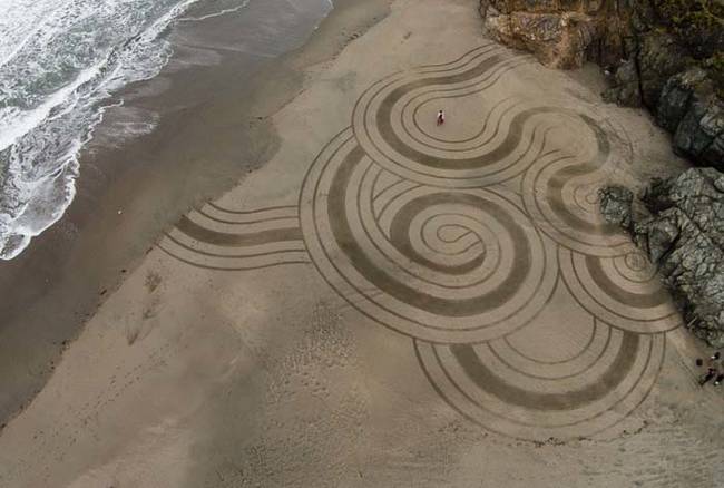 Artista faz sucesso criando arte temporária em areia de praia